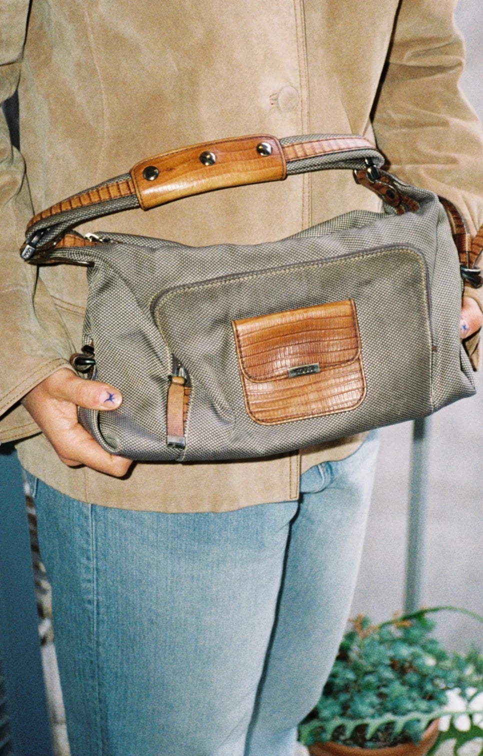Khaki bag with leather details carried under the arm