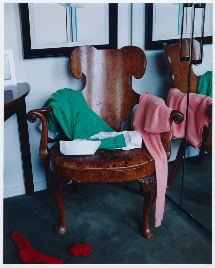 Green and pink knits draped over an antique carved chair