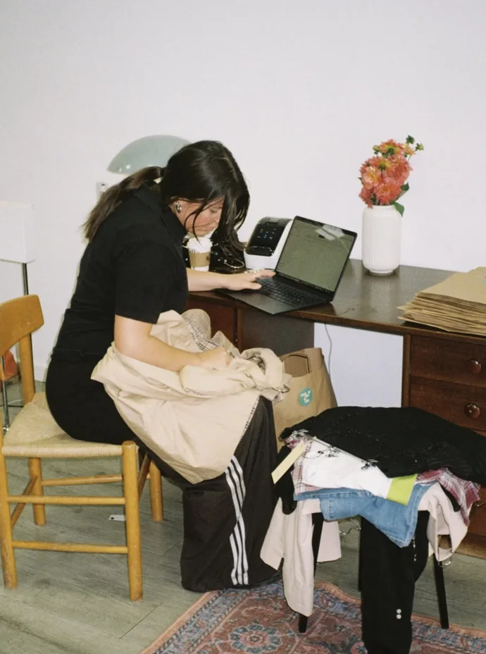 Sorting through clothes at a desk before a pop-up