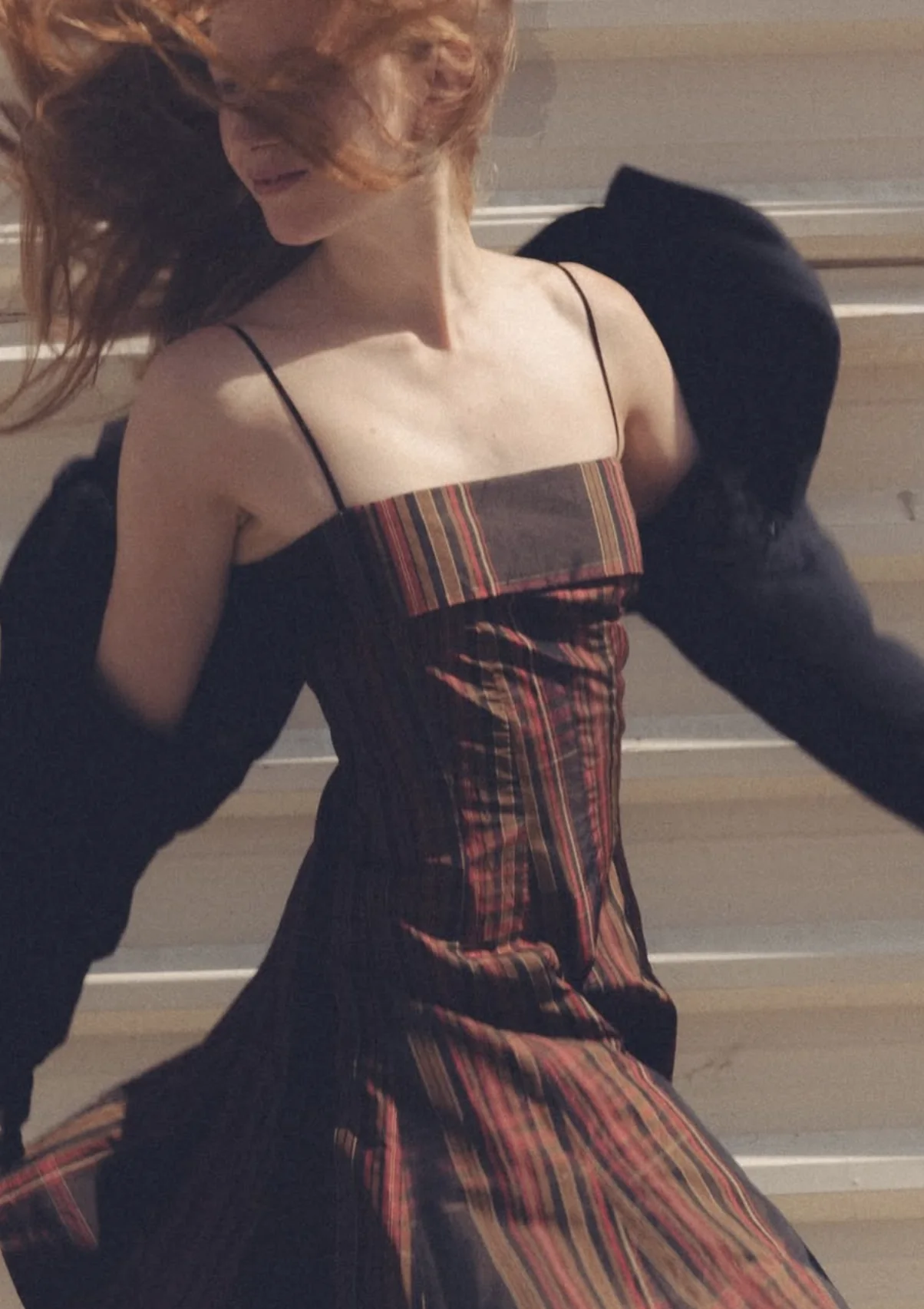 Woman in a striped dress and dark jacket mid-stride